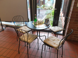 Cafétisch mit drei Stühlen und einer Flasche.